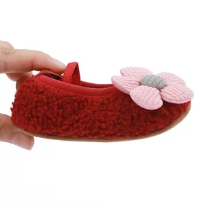 Close-up of red fleece baby pre-walker shoe with soft sole and pink flower decor.