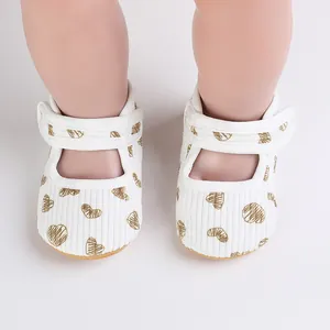 Detailed view of white baby walking shoes with gold heart patterns and velcro strap