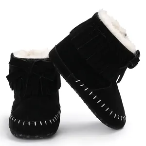Close-up view of black suede baby boots with tassels, white fur lining, and bow detail
