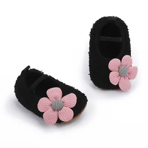 Detailansicht von schwarzen flauschigen Babyschuhen mit rosa Strickblume und weicher Sohle