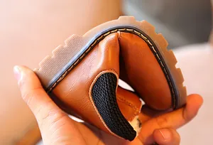 Vista detallada que muestra la suela de goma suave y flexible de bota para niños marrón