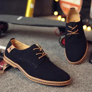 Dettaglio di scarpe derby da uomo in camoscio nero con lacci marroni e suola