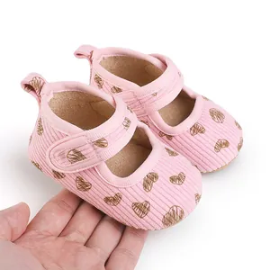 Detail view of pink baby walking shoes with heart print and soft corduroy fabric texture.