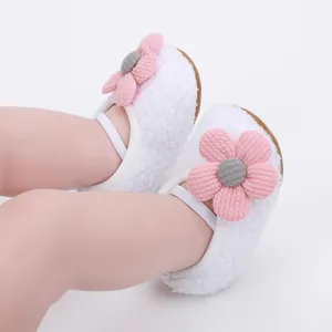 Detail of white plush baby walking shoes featuring a soft sole and pink flower decoration