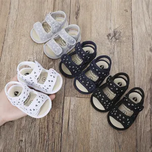 Close-up of colorful baby sandals with triangle patterns on a rustic wooden surface