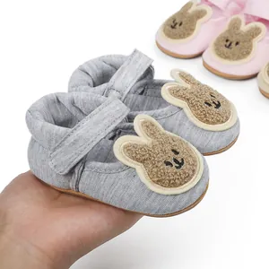 Detail of soft grey pre-walker infant shoes with cute plush rabbit patch and velcro strap