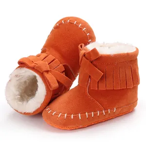 Detailed macro view of orange baby tassel boots featuring soft white faux fur lining and bow