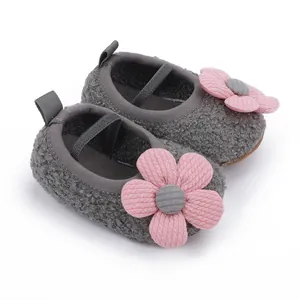 Detailansicht von grauen flauschigen Babyschuhen mit rosa Blume und einer weichen Sohle.