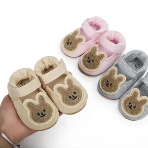 Detalle de zapatos suaves de algodón para bebé con parches de conejitos animados.