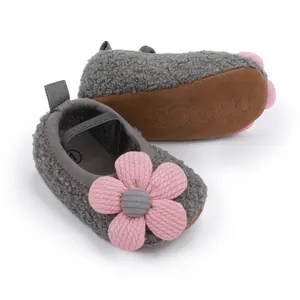 Nahaufnahme grauer flauschiger Babyschuhe mit rosa Blume und weicher rutschfester Sohle.