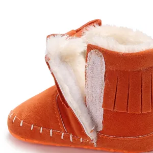 Macro view of soft orange suede baby bootie with fringe and warm faux fur lining