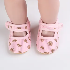 Close-up of pink baby walking shoes with brown heart patterns and velcro straps