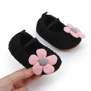 Close-up of black fuzzy baby shoes with pink flower detail and soft sole