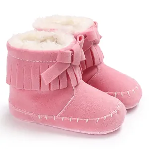 Detail view of pink baby fringe boots with warm plush lining and bow decoration.