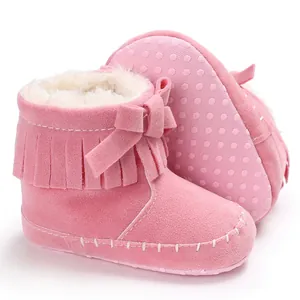 Detailed view of pink infant fringe boots featuring soft sole, bow accent, and fluffy lining