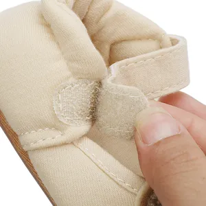 Close-up of beige baby shoe featuring an adjustable hook-and-loop strap detail