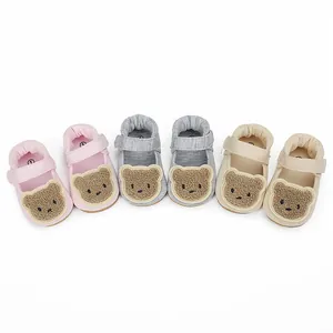 Drei Paar Baby-Lauflernschuhe mit süßen Bären-Patches in den Farben Rosa, Grau und Beige.