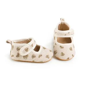 Detail of beige corduroy baby walking shoes with brown heart patterns and strap
