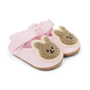 Detalle de zapatos de bebé rosa para primeros pasos con conejo de peluche y velcro