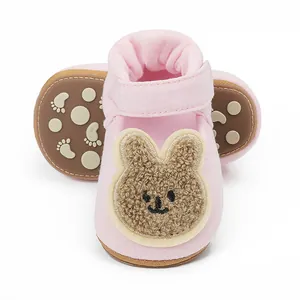 Detalle de zapatos rosas para bebé con parche de conejo de peluche y suela antideslizante