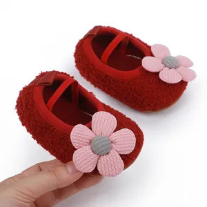 Detailed close-up of red soft-sole fleece baby shoes featuring a cute pink flower decoration