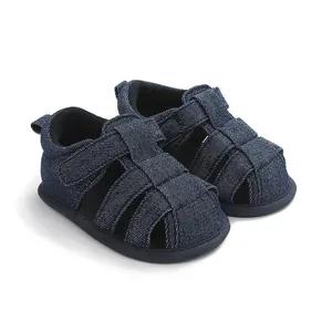 Primer plano de sandalias para bebé en mezclilla azul marino con correas de velcro.