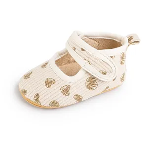 Close-up of beige infant walker shoes with gold heart patterns and Velcro strap