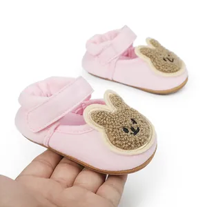 Primer plano de zapatos de bebé rosa con un parche de conejo de peluche marrón claro