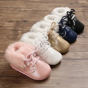 Variety of colorful baby fur-lined walking boots with soft soles on wood background