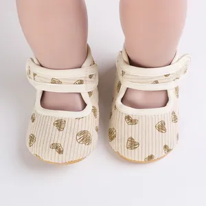 Detail view of beige corduroy baby walking shoes with heart print and strap closure