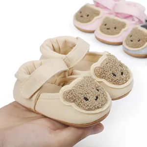 Close-up of beige baby walking shoes with cute cartoon bear design and soft sole