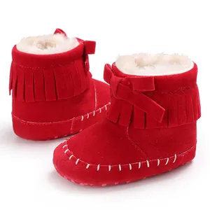 Close-up macro view showing texture of red suede baby boots with fringe and bow