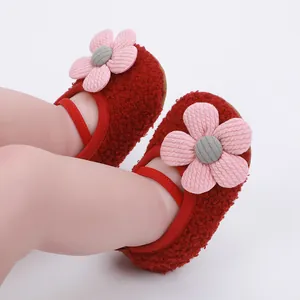 Detailed macro view of red plush baby walking shoes featuring a cute pink flower decoration