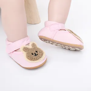 Detalle de zapatos de bebé rosa con cara de conejo peludo y suela antideslizante.