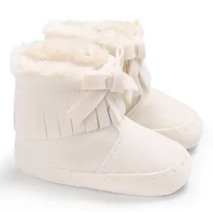 Detail view of off-white fringe baby boots with warm plush lining and a cute bow