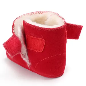 Detail van rood suède babybootie met warme witte voering van imitatiebont en klittenband