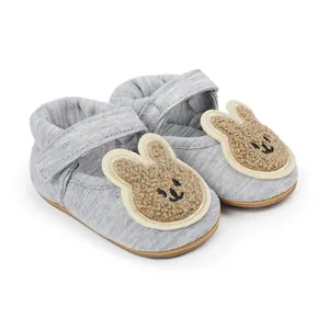 Detalle de la cabeza de conejo de peluche en zapatos grises de algodón para bebés pre-walker