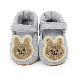 Detalle de zapatos grises para bebé con un parche de oso lindo y correa de velcro
