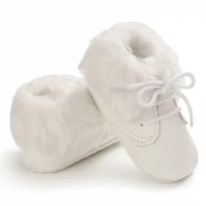 Close-up detail of white infant fur boots with soft soles and lace-up design