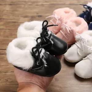 Macro detail of infant soft-sole black faux fur boots with laces for cozy winter warmth.