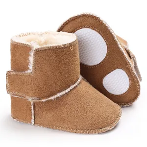 Primer plano de botas de invierno marrones para bebé con forro de piel sintética blanca y suela.