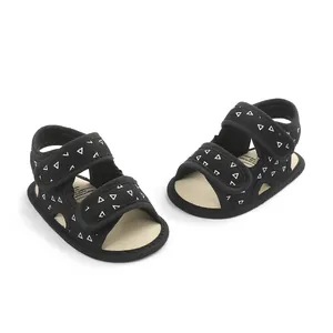 Black baby summer sandals with white triangle patterns and double velcro straps.