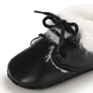 Macro view of black infant walking boot featuring soft white faux fur lining and black laces