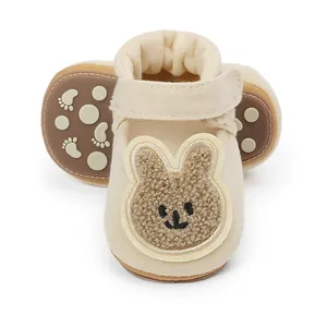 Vista detallada de zapatos de bebé beige con diseño de conejo animado y suave textura