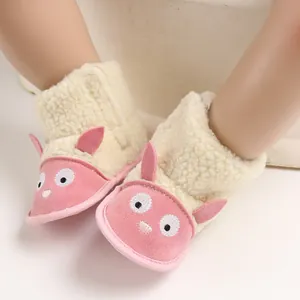 Gros plan sur des bottes de neige roses pour bébé avec motif mouton et polaire.