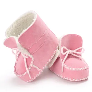 Dettaglio degli stivaletti invernali rosa per neonati con calda fodera in pile e lacci bianchi.