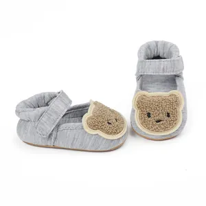 Close-up of grey baby walking shoes with cute brown teddy bear plush patch.