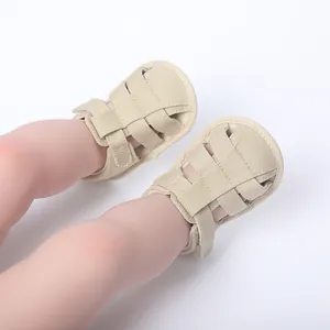 Primer plano de sandalias de bebé transpirables beige con correas suaves y velcro.