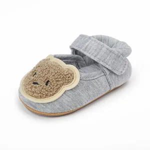 Nahaufnahme eines grauen Lauflernschuhs für Babys mit süßem Teddybär-Plüschaufnäher