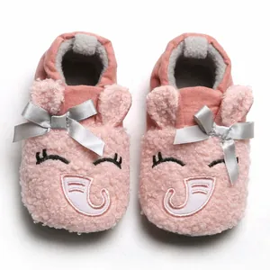 Close-up detail of pink fuzzy baby booties featuring a cute embroidered cartoon face